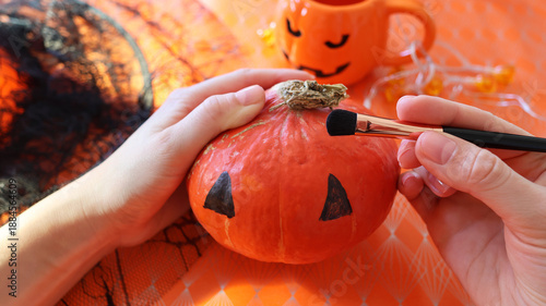 Handmade pumpkin painting on an orange background with a spider web 