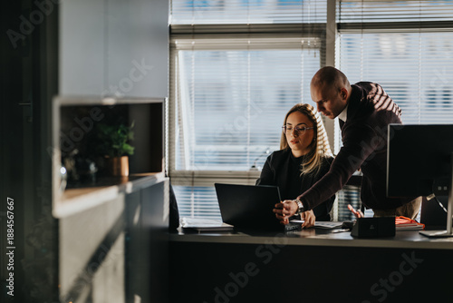 Valokuva Two professionals work together at a desk, one guiding the laptop