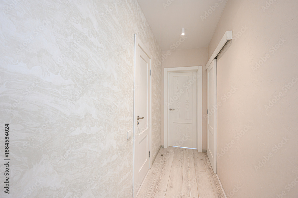 Fototapeta premium narrow, light-toned hallway with textured wallpaper, light wooden flooring, three white doors, recessed ceiling light, minimalist design, neutral palette.