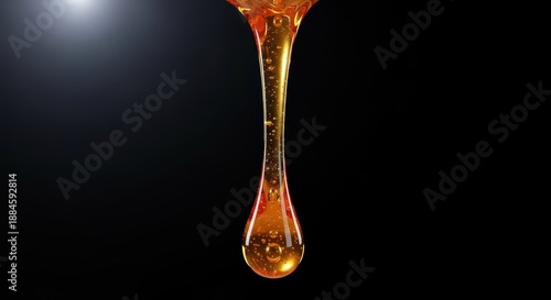 A viscous amber fluid stretches tightly and dramatically as it drips slowly downward, highlighting the strong molecular adhesion characteristic, elasticity, texture, property