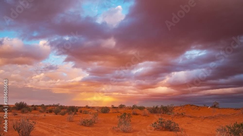Timelapse: sunset over the desert near Ksar Ghilane, Tunisia, with red sand dunes and dramatic colorful clouds, conveying serenity and a timeless Sahara landscape ideal for travel and lifestyle themes
