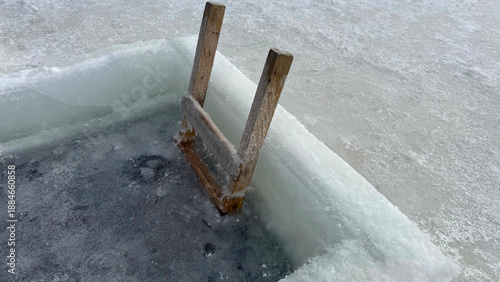 Foto Wooden ladder steps for ice hole swimming in frozen lake surface with thick ice