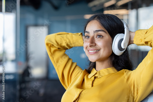 Fotografija Close-up photo of a young Indian woman wearing headphones sitting in an office,