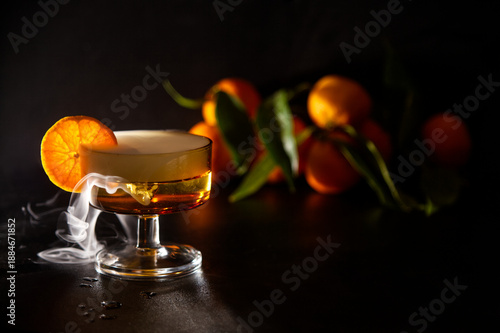 Elegant Cocktail With Orange Slice Garnish And Dramatic fresh misty effect In A Glassware Setting and Fresh Oranges in Background