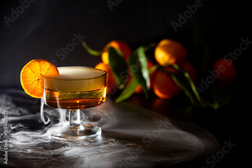 Elegant Cocktail With Orange Slice Garnish And Dramatic fresh misty effect In A Glassware Setting and Fresh Oranges in Background