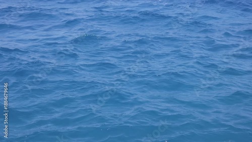 Close-up view of blue ocean water with gentle ripples and small waves. Slow motion.