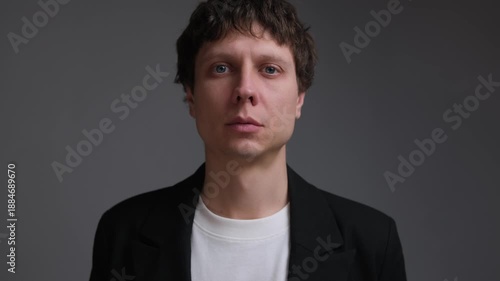 Man nods in reluctant agreement, anxious expression portrait on neutral background.