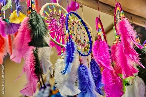 Colorful handcrafted dreamcatchers with vibrant feathers displayed in an Ecuadorian souvenir market, showcasing intricate designs and cultural craftsmanship in a lively setting