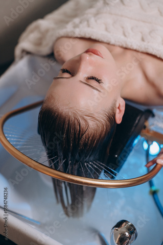 Young woman receiving a head massage during a Japanese head spa treatment with water flowing from a special hair washing tool.