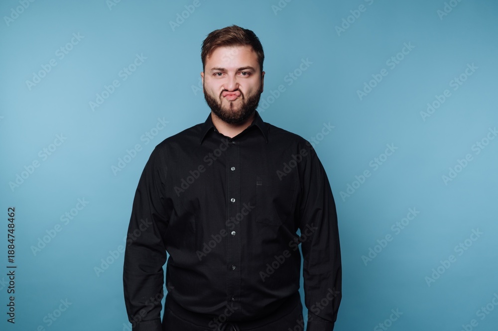 Obraz premium Man in black shirt making a funny face against blue background.
