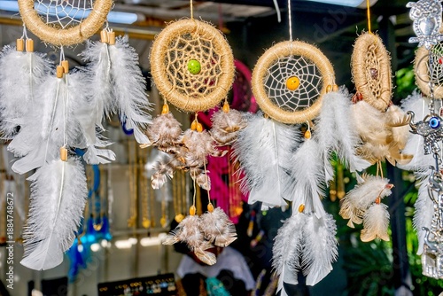 Handcrafted Ecuadorian dreamcatchers with colorful beads and feathers displayed in a vibrant market setting, showcasing traditional artisan craftsmanship and cultural heritage