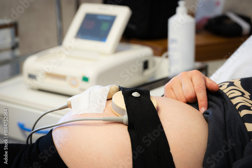 Pregnant woman undergoing non-stress test (nst) in a medical clinic, receiving prenatal care for fetal monitoring, ensuring maternal and infant health during pregnancy