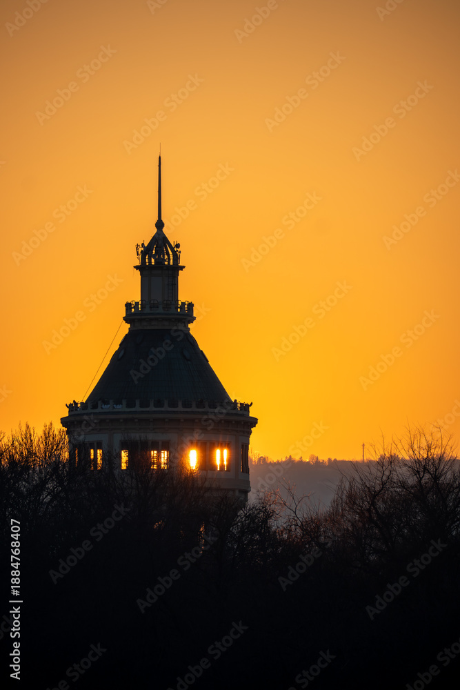 Photography Sunset light shines through the windows of a historic domed building, creating a dramatic silhouette against a warm orange sky