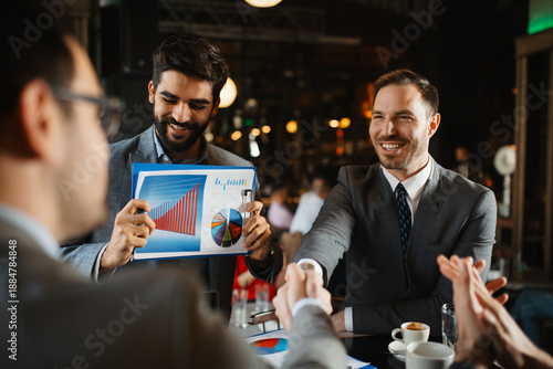 Tableau sur toile Two businessmen shaking hands across a table in a cafe, finalizing a deal or par