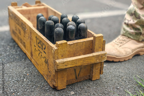 Foto Military crate with black practice hand grenade case on asphalt