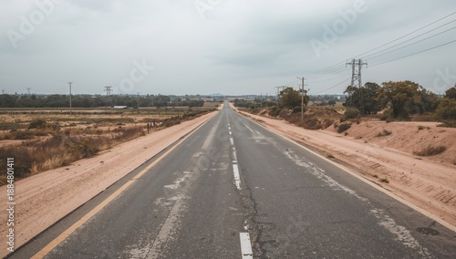 Empty Road Stretches Through Countryside Under Cloudy Sky in Midday