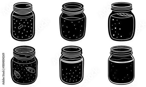 Six jars filled with pickled vegetables are arranged on a table indoors.