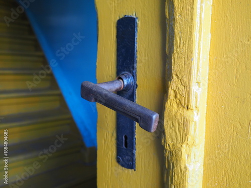 old yellow door with old metal lever door handle	