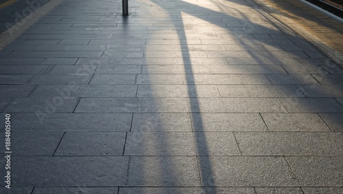 Sunlight Casts Long Shadows on the Pavement at a Train Station in the Late Af...