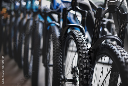 Close-up view of a row of new mountain bikes in a bicycle shop, focusing on tires and suspension.