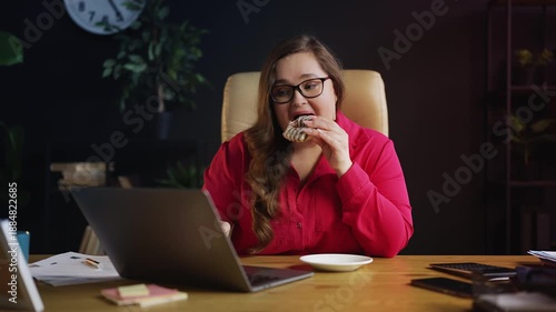 Wallpaper Mural Plus size businesswoman eating donut at workplace, unhealthy high sugar snack Torontodigital.ca