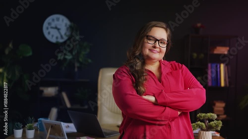 Happy businesswoman folding arms and smiling confidently in office interior