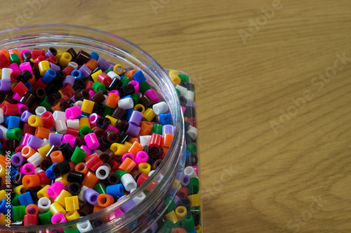 A clear plastic jar filled to the brim with multi-colored plastic cylinders, representing the abundance of synthetic materials.