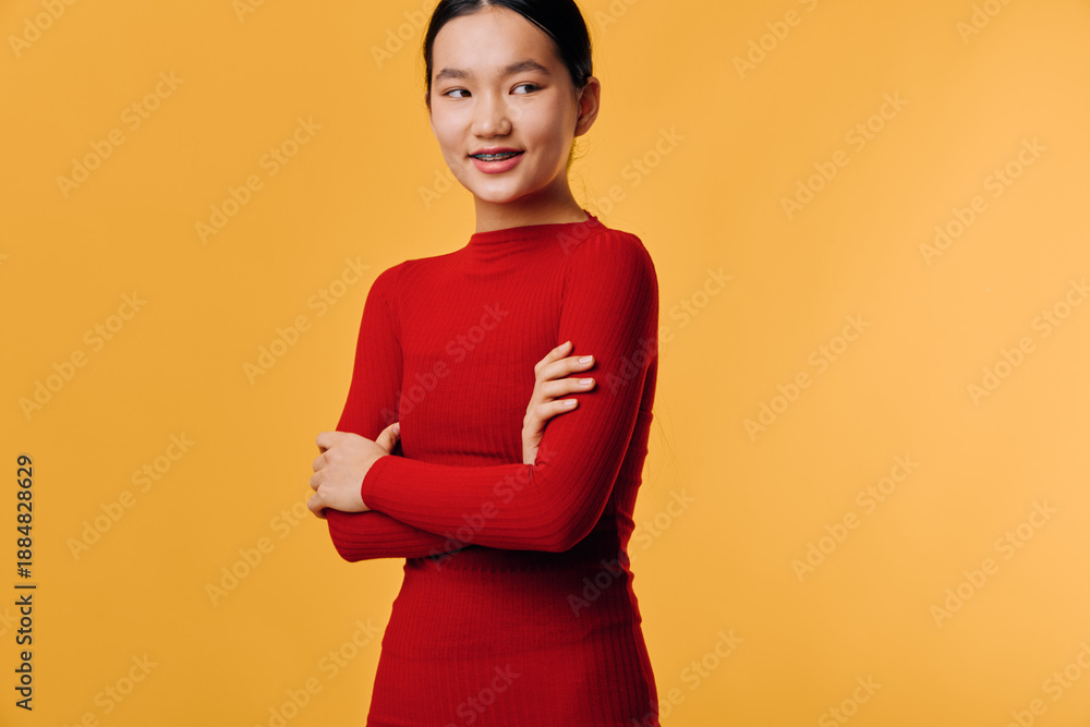 Obraz premium Young woman smiling with crossed arms in red long sleeve shirt against yellow background. Portrait of confident female with casual outfit and natural makeup for lifestyle concept.