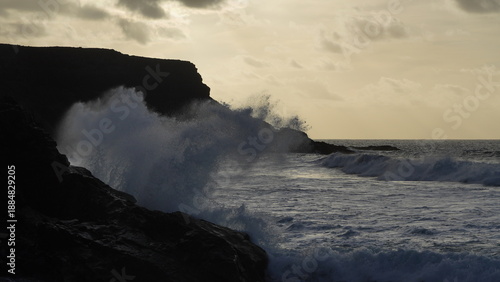 Spectacular sunset contemplating the force of the sea crashing agains the cliff