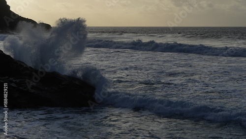 Spectacular sunset contemplating the force of the sea crashing agains the cliff