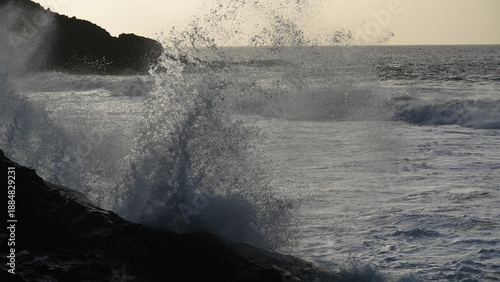 Spectacular sunset contemplating the force of the sea crashing agains the cliff
