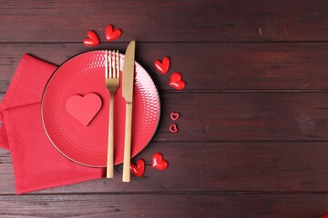 Valentine's Day. Elegant setting with cutlery and decorative hearts on wooden table, flat lay. Space for text