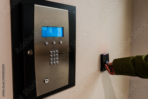 Foto A person uses a key to access a building with a security system that features a keypad and a card reader