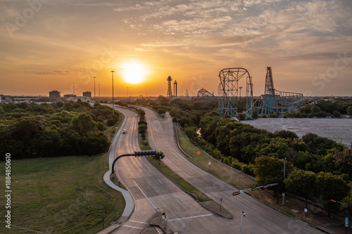 Obraz na płótnie Aerial Drone View of Rollercoaster Rides Near Busy Highway Roads With Bright Ora