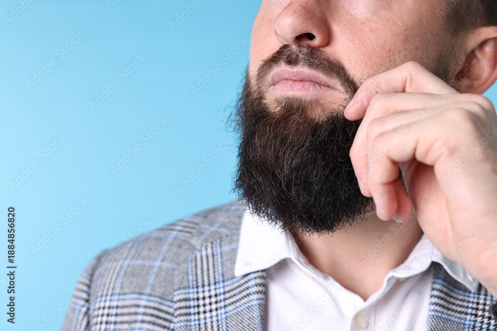 Fototapeta premium Man with mustache and beard on light blue background, closeup. Space for text