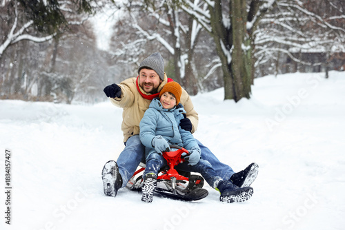 Fotografie Happy father and his son with sledge outdoors on winter day