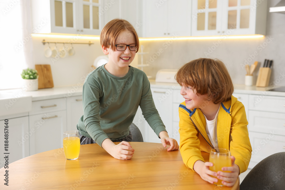 © New Africa - Cute brothers with orange juice at wooden table in kitchen © New Africa - Cute brothers with orange juice at wooden table in kitchen