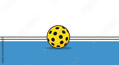 A close-up of a yellow pickleball with black dots on a blue court with white lines, highlighting the texture and design of the sports ball.