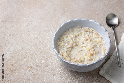 Multigrain cereal porridge made from mixed grain flakes including rye, oats, barley, buckwheat and wheat. Minimal breakfast scene with milk, soft light and empty space for text