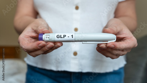 GLP-1 injection pen held by woman in front of abdomen, weight management concept