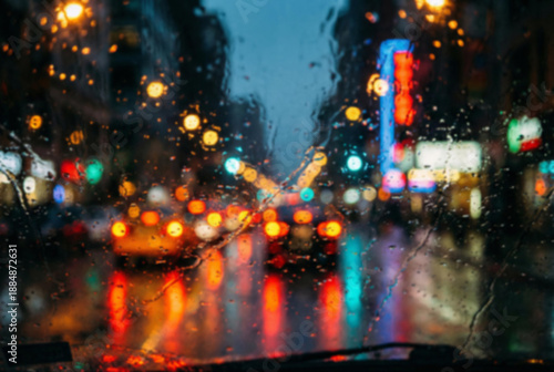 Rainy city street at night with blurred lights seen through a wet window