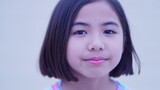 Young asian girl looking at camera with a subtle smile, embodying childhood innocence and joyful expression
