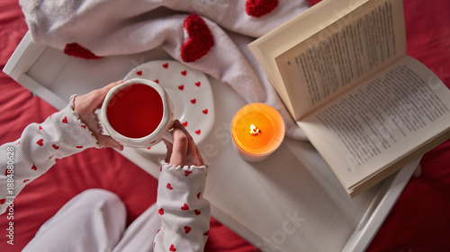 Cozy morning with a book, hot drink, and a candle, decorated with hearts © shine.graphics