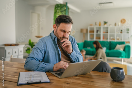 Foto Man concentrating working from home with family in background