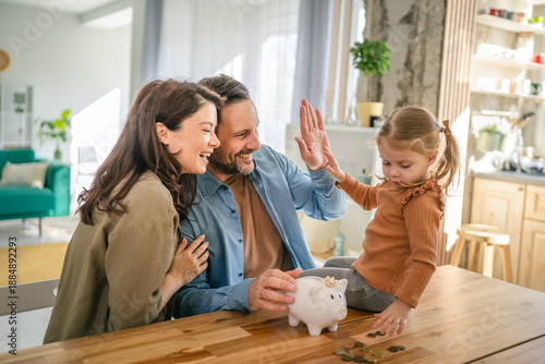 Fotografía Family saving money in piggy bank, high five for financial success