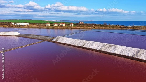 Wallpaper Mural A stunning display of salt pans captures the eye with vibrant red hues reflecting the sky. Workers diligently harvest salt while scenic homes dot the green landscape. Torontodigital.ca