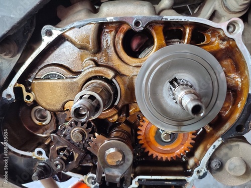 Foto Close-up of an open motorcycle engine crankcase showing internal gears, shafts, and mechanical components covered in engine oil during repair or maintenance in a workshop