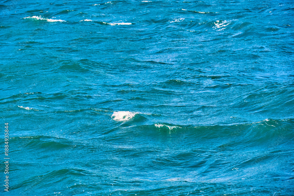 Naklejka premium Blue ocean waves with white foam on a sunny day