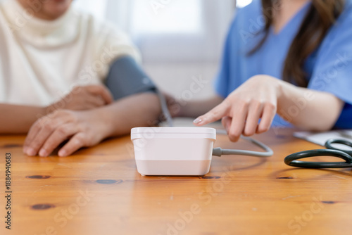 Foto Close-up of nurse using digital blood pressure monitor to check senior patient health, Concept of home healthcare service, chronic disease management, elderly medical care