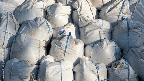 A large pile of white sacks lined up on top of each other full of sand and construction waste material